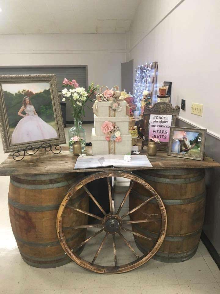 an old barrel table with a wedding cake on top and other items in the background