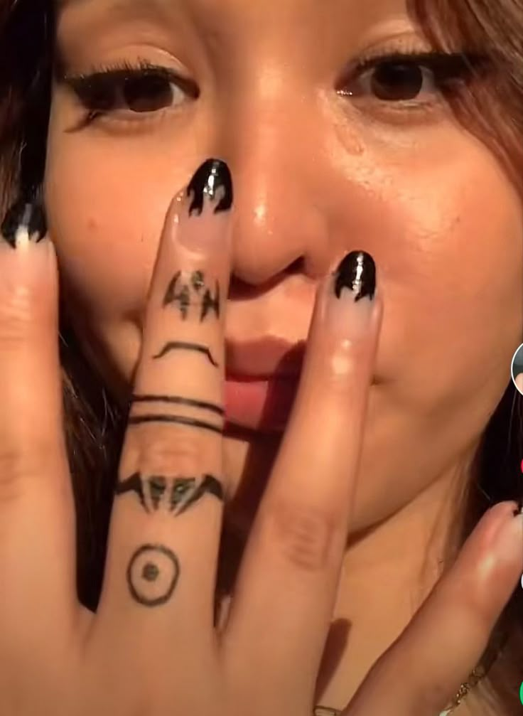 a woman with black and white nail polish holding her hand up to her face