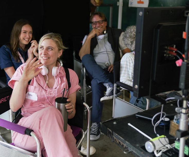 two women in pink scrubs are sitting on a chair and talking on the phone