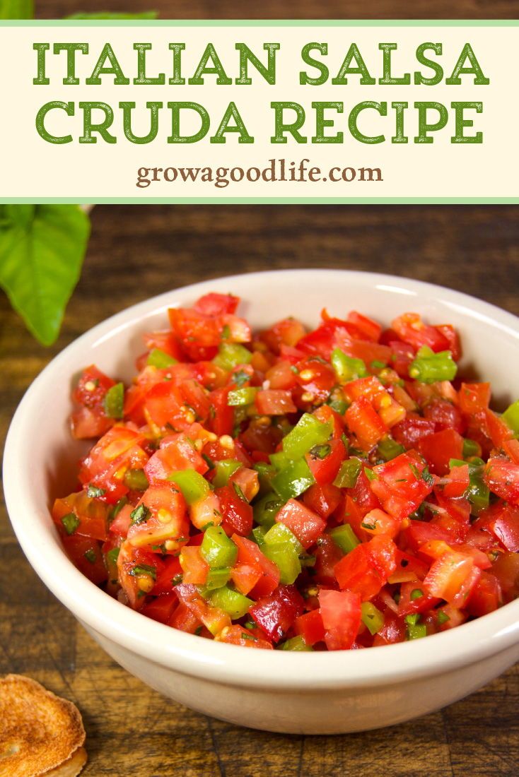 a white bowl filled with chopped tomatoes and green peppers on top of a wooden table