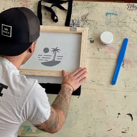 a man is working on a painting with his hands in front of the frame and tools around him