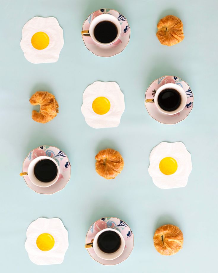 an overhead view of coffee, croissants and eggs on a blue surface