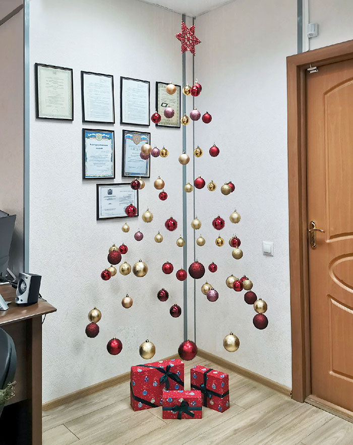 a decorated christmas tree in an office cubicle with presents on the floor next to it