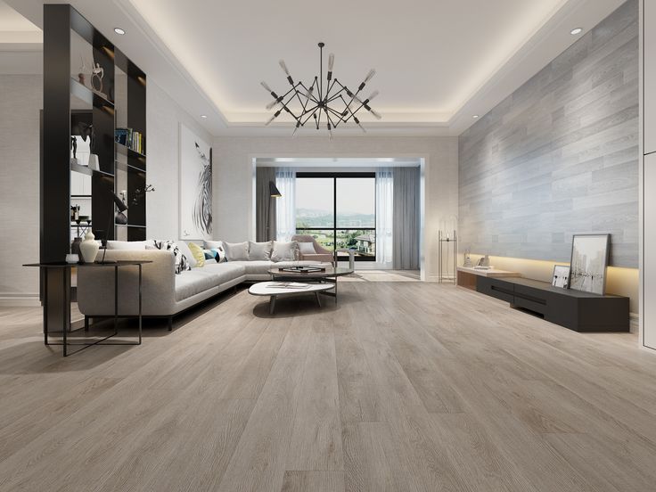 a living room with wood flooring and white furniture in the center is lit by a chandelier