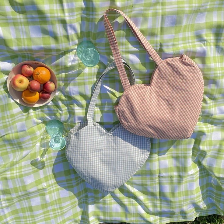 a bag and bowl of fruit are laying on a green plaid blanket next to a bowl of oranges