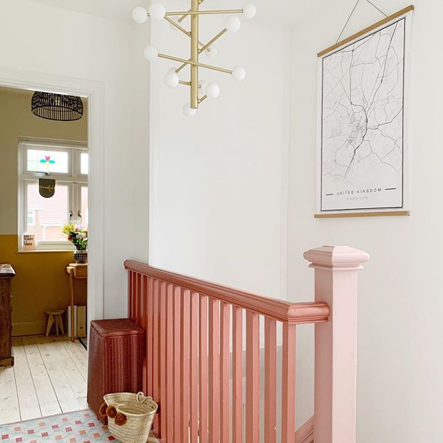 a hallway with pink railing and white walls