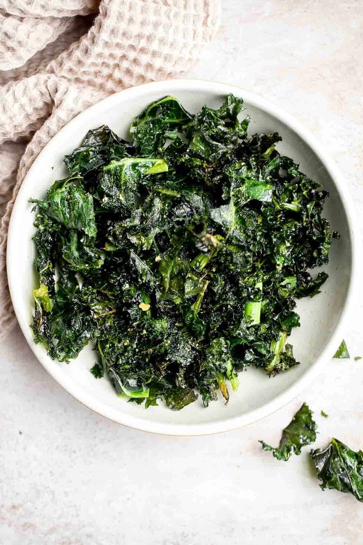 a white bowl filled with greens on top of a table