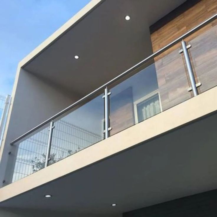 a balcony with glass railings and wood paneling on the side of a building