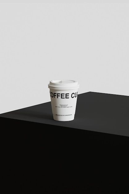 a cup of coffee sitting on top of a black counter next to a white wall