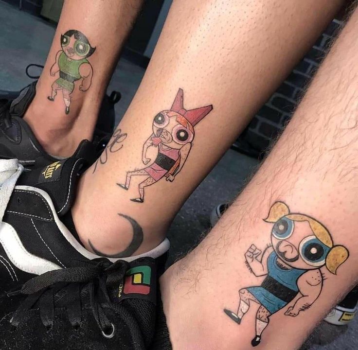 two people with tattoos on their legs and one has a cartoon character tattooed on the leg