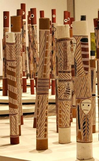 several tall wooden poles with faces on them in a room filled with mirrors and sculptures