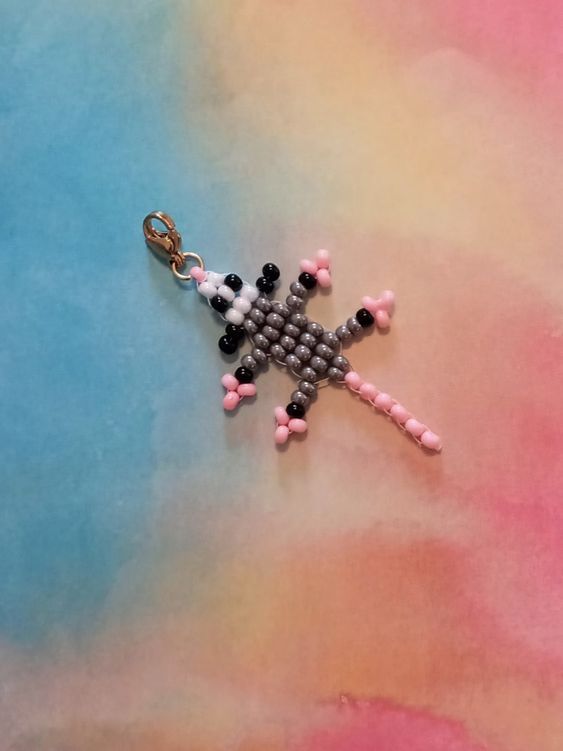 a cross made out of beads on a blue and pink background