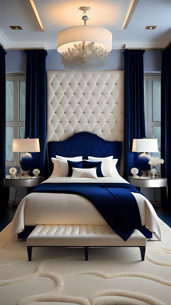 a bedroom with blue and white bedding, chandelier, pillows and lamps