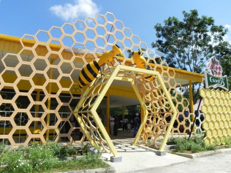 a yellow building with a bee sculpture in front of it