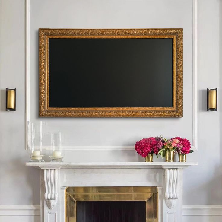 a fireplace in a living room with a painting on the wall and vases filled with flowers