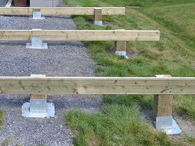 three wooden benches sitting on top of gravel and grass next to a fenced in area