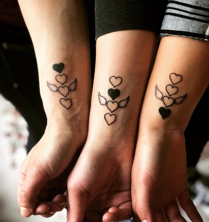 two girls with matching tattoos on their arms holding each other's hands in the shape of hearts