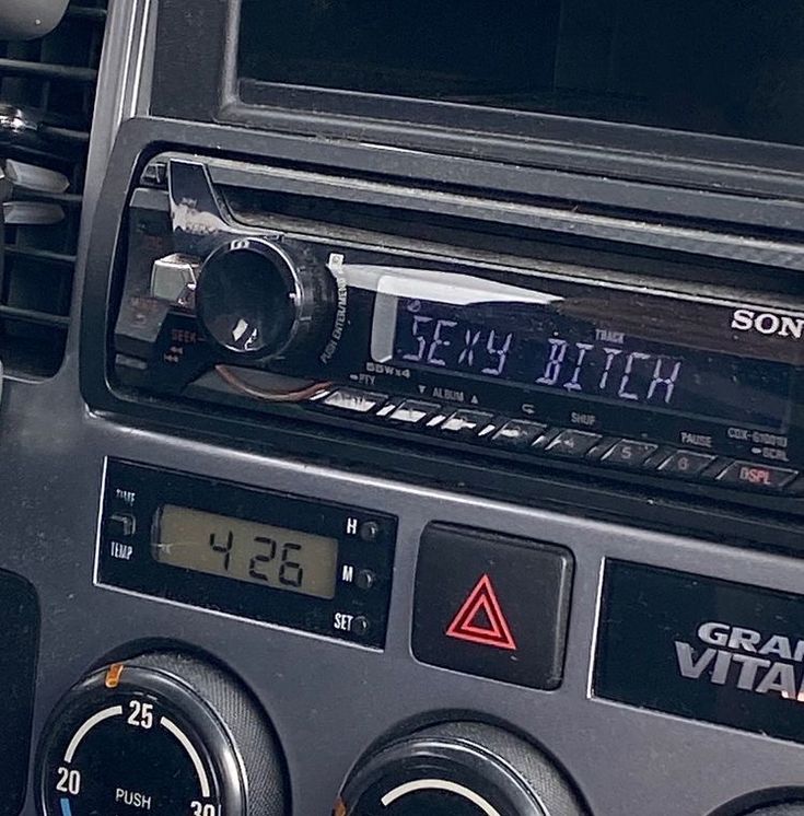 an old radio with the time displayed on it's display screen, in front of a car dashboard