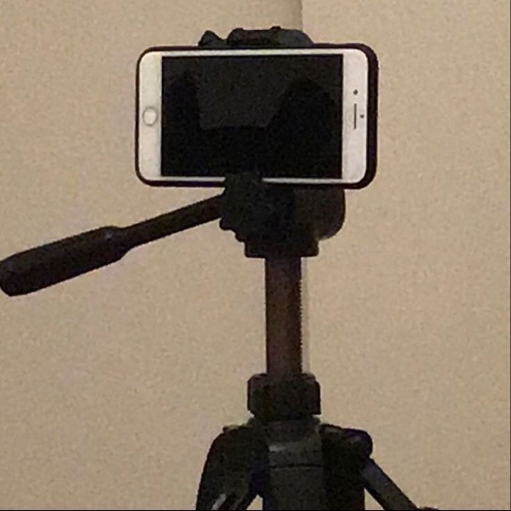 a cell phone sitting on top of a tripod in front of a white wall