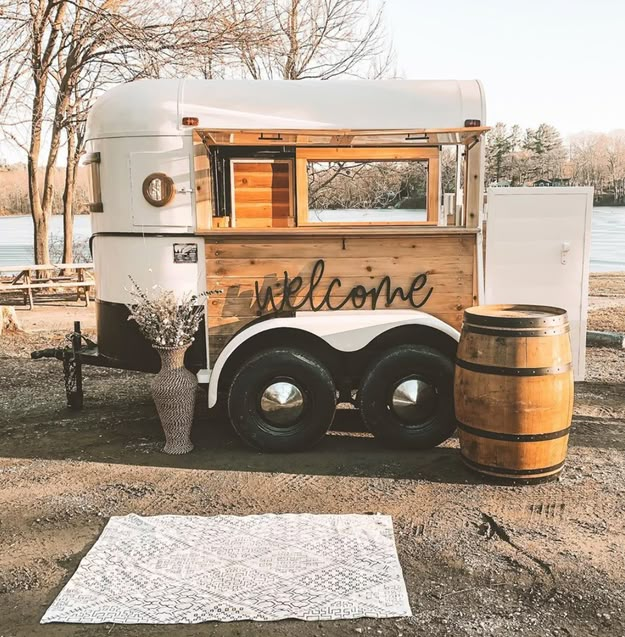 an old truck with the word welcome painted on it's side and barrels next to it