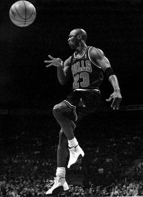 an old photo of a basketball player jumping up to dunk the ball in black and white