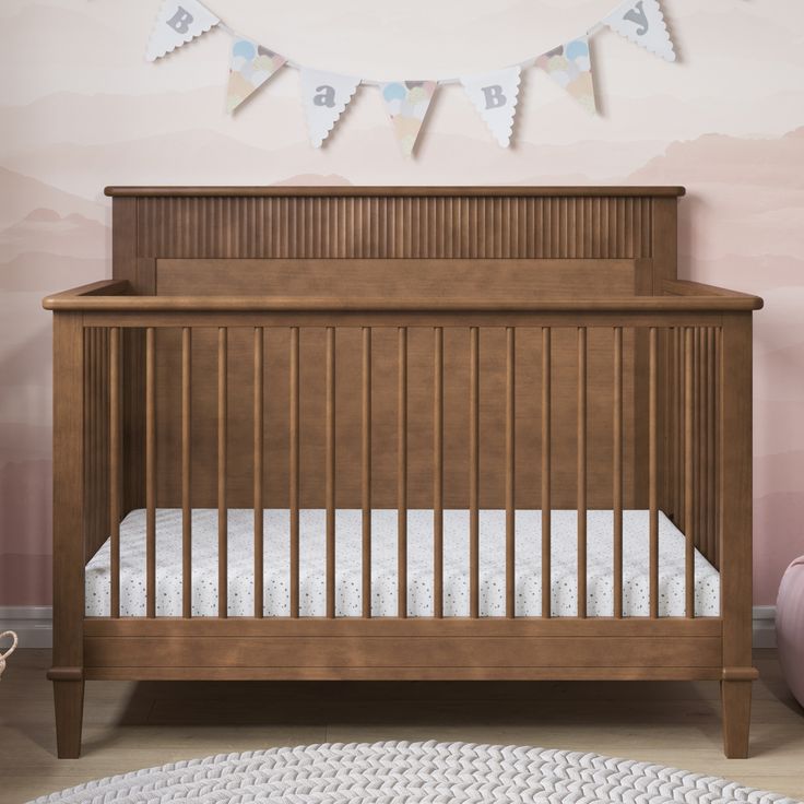 a baby crib in a pink room with bunting flags above the crib