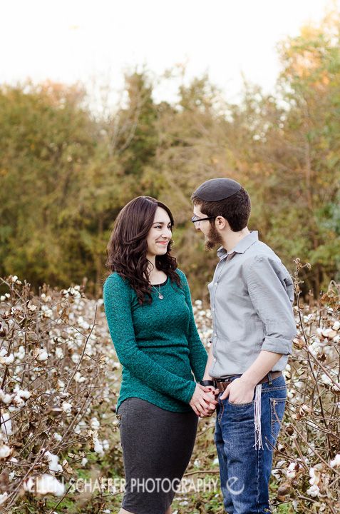 a man and woman standing next to each other in a cotton field