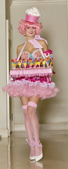 a woman dressed in pink is holding a large tray of candies and lollipops