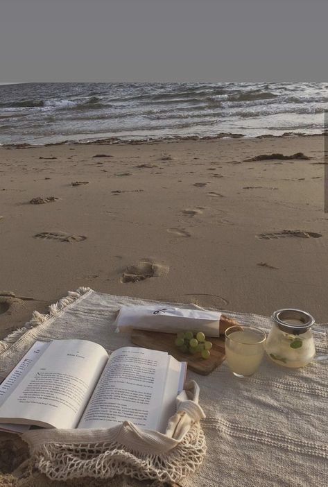 an open book on the beach next to some drinks