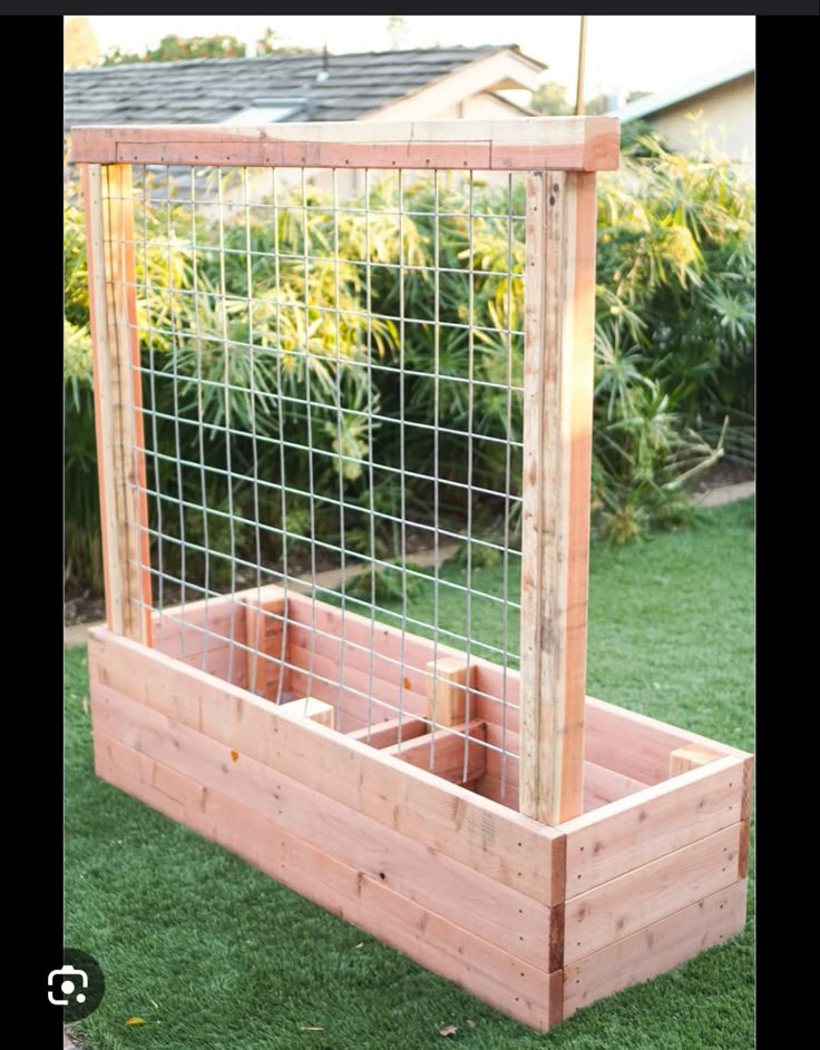 a wooden planter filled with plants on top of grass