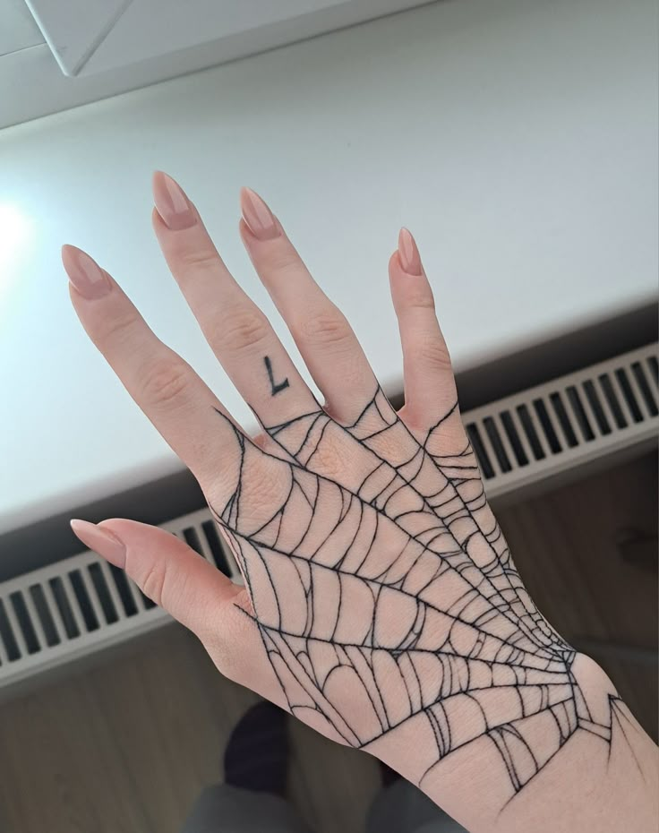 a person's hand with a spider web tattoo on it