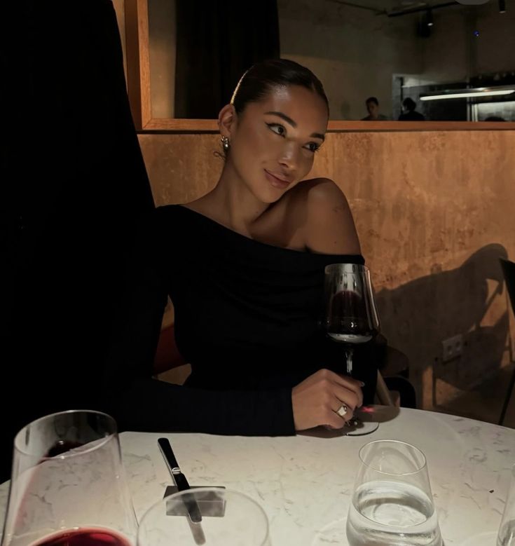 a woman sitting at a table with a glass of wine