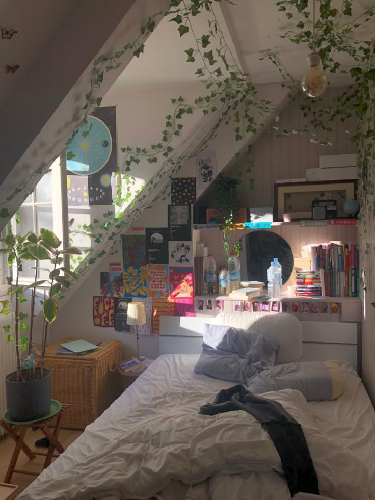 an attic bedroom with plants growing on the wall and bed in the foreground, under a slanted ceiling