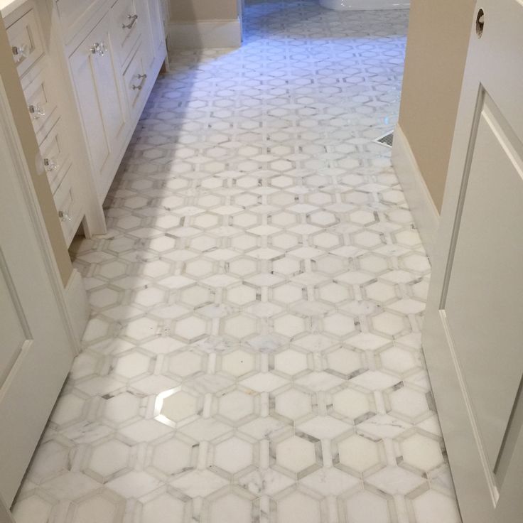 a white bathroom with hexagonal tiles on the floor