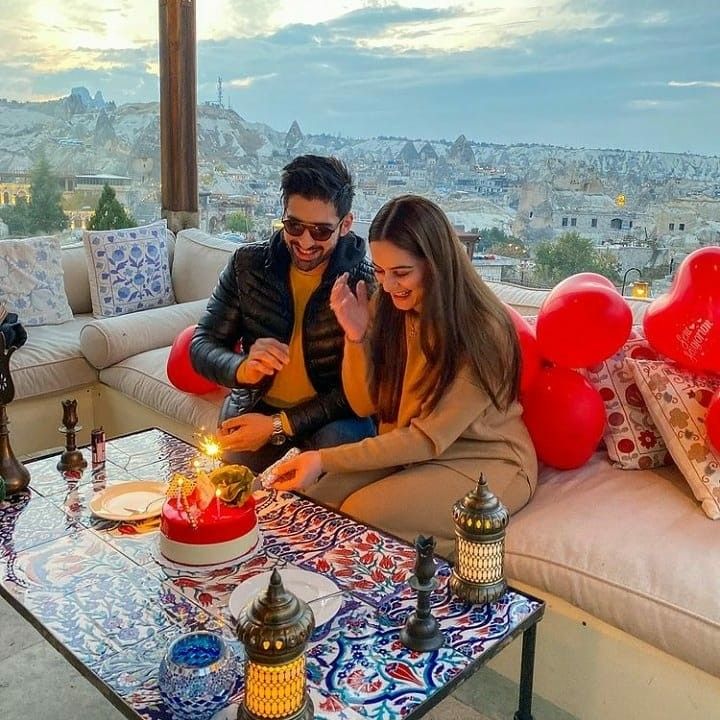 two people are sitting on a couch with a cake and candles in front of them