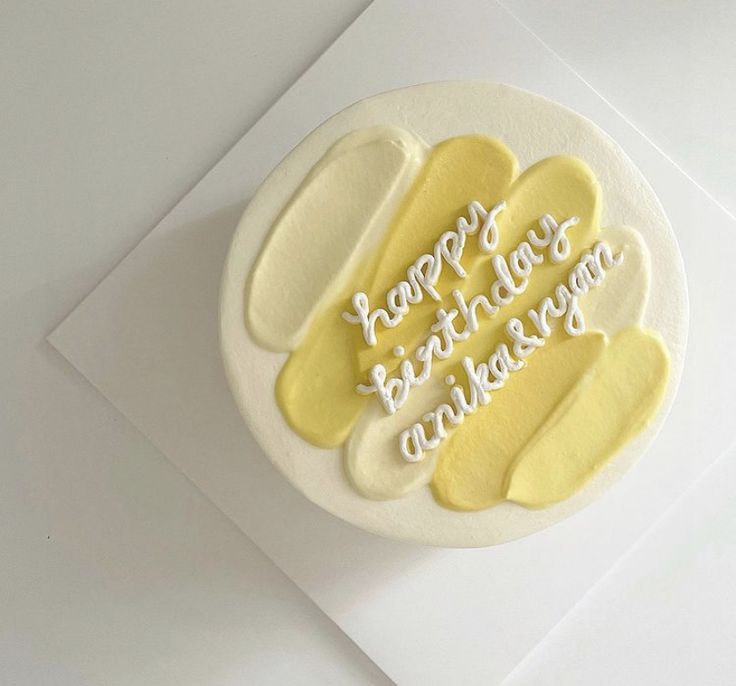 a birthday cake with white frosting and yellow icing