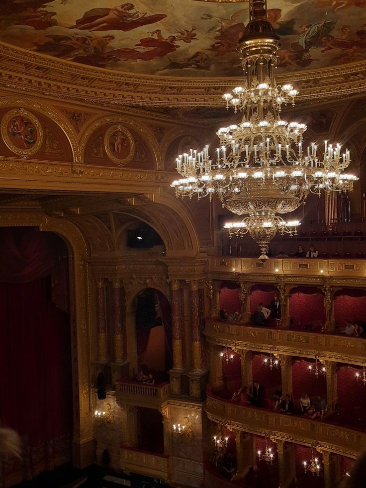 a chandelier hangs from the ceiling in an ornately decorated auditorium