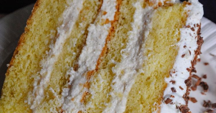 a close up of a slice of cake on a paper plate with white frosting