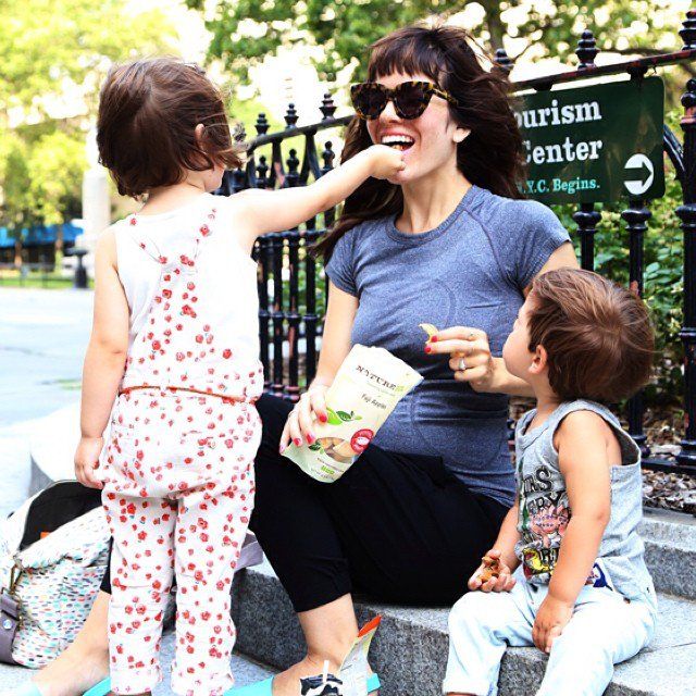 a woman sitting on the steps with two small children and one is feeding her food