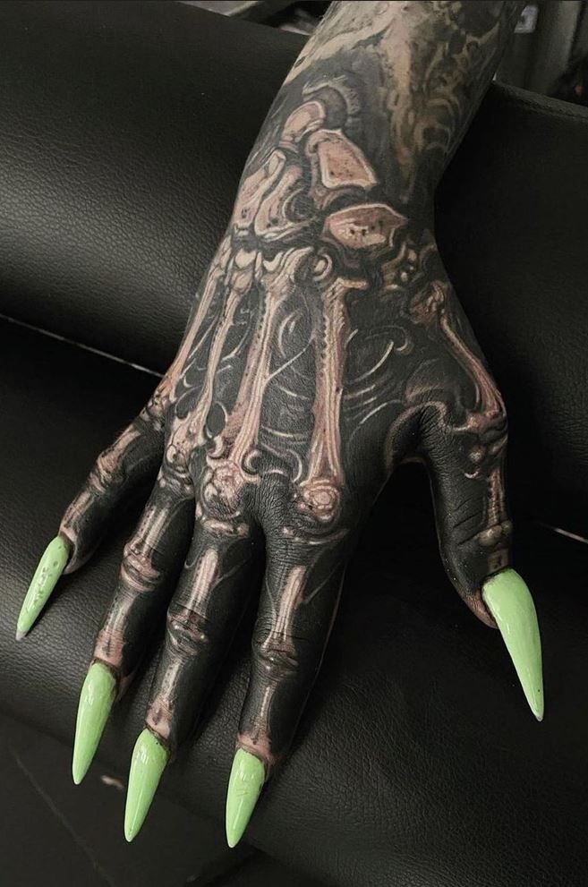 a person's hand with green nails and tattoos on it