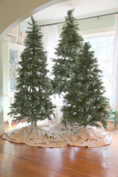 two fake christmas trees sitting on top of a wooden floor