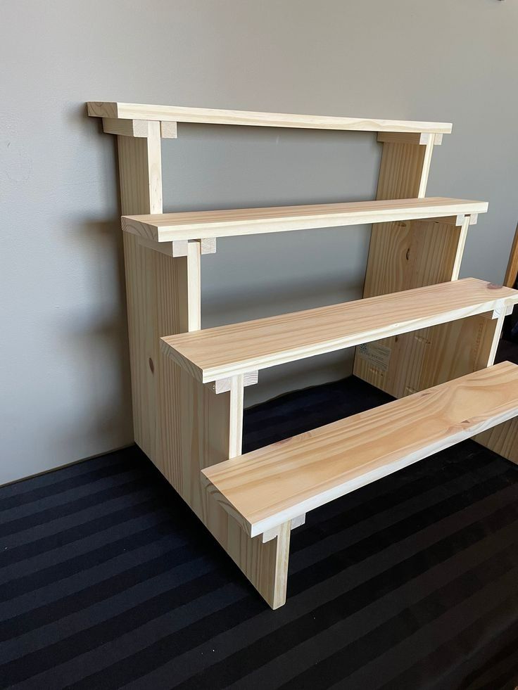 a set of three wooden shelves sitting on top of a carpeted floor next to a wall