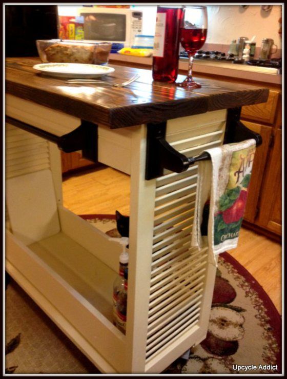 a kitchen island with an open drawer on the bottom and wine glasses on top in front of it