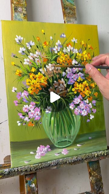 someone is painting flowers in a green vase