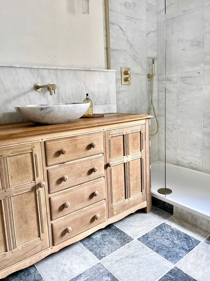 a bathroom with a checkered tile floor and wooden cabinetry, along with a marble counter top