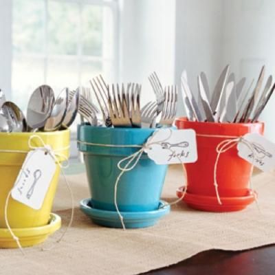 four pots with forks and spoons in them sitting on a table next to each other