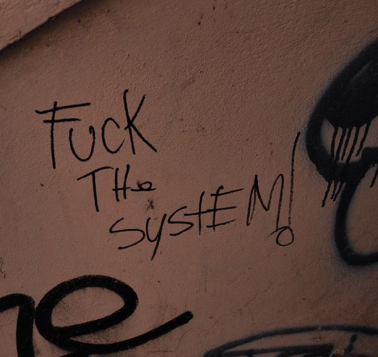 graffiti written on the side of a building reads, fock the system'20