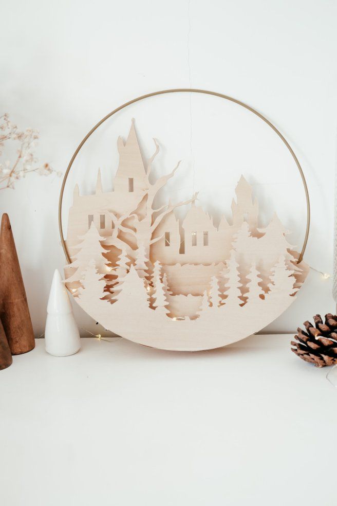 a wooden cutout of a castle surrounded by pine cones and other decorations on a white surface