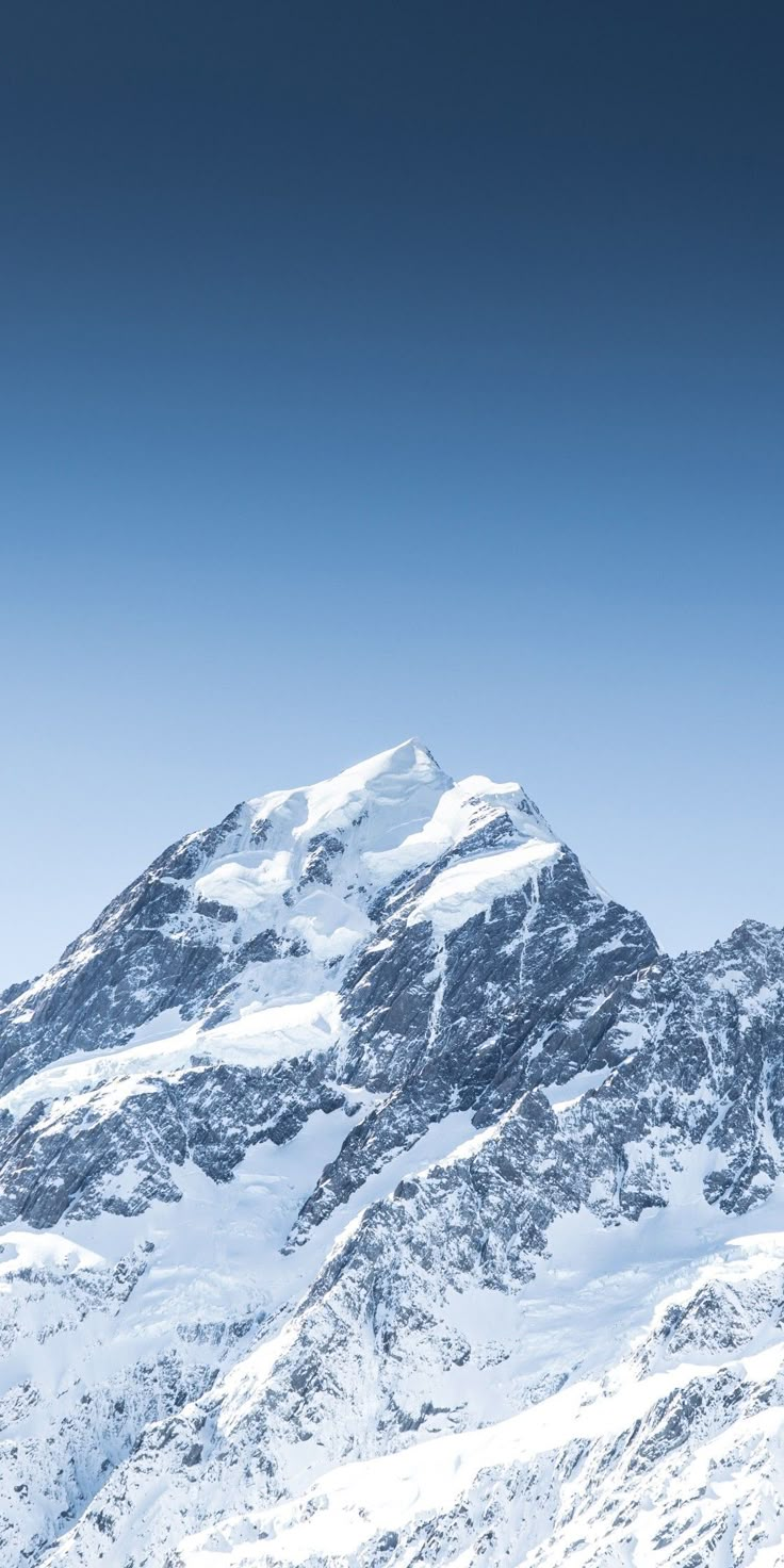 a man riding skis down the side of a snow covered mountain under a blue sky