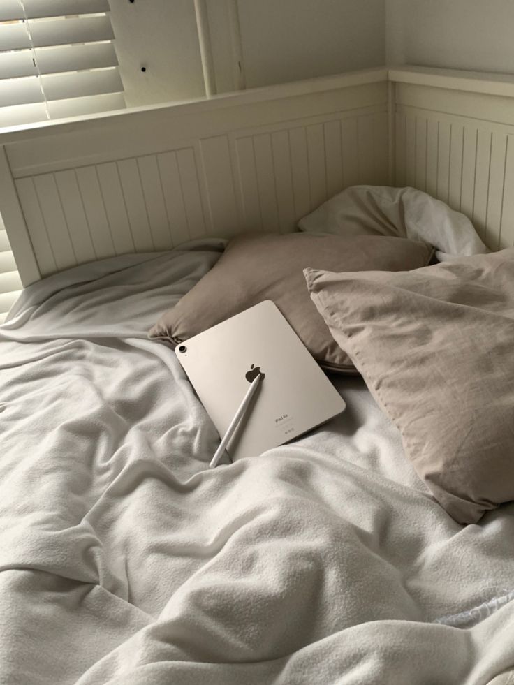 an open laptop computer sitting on top of a bed next to pillows and pillow cases